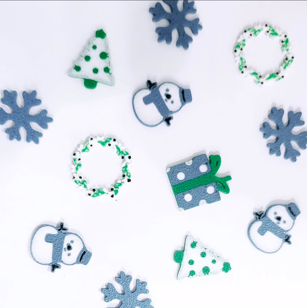 Custom 3D printed pieces by Aurelis Design Studio of Christmas-themed decorative items including trees, snowflakes, and snowmen on a white background.