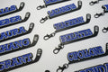Multiple hockey stick keychains with player names and numbers printed on them in 3 layers with the base in black, the middle layer is white and the name and number is in blue
