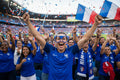 people in blue shirts celebrating with French flags in a stadium